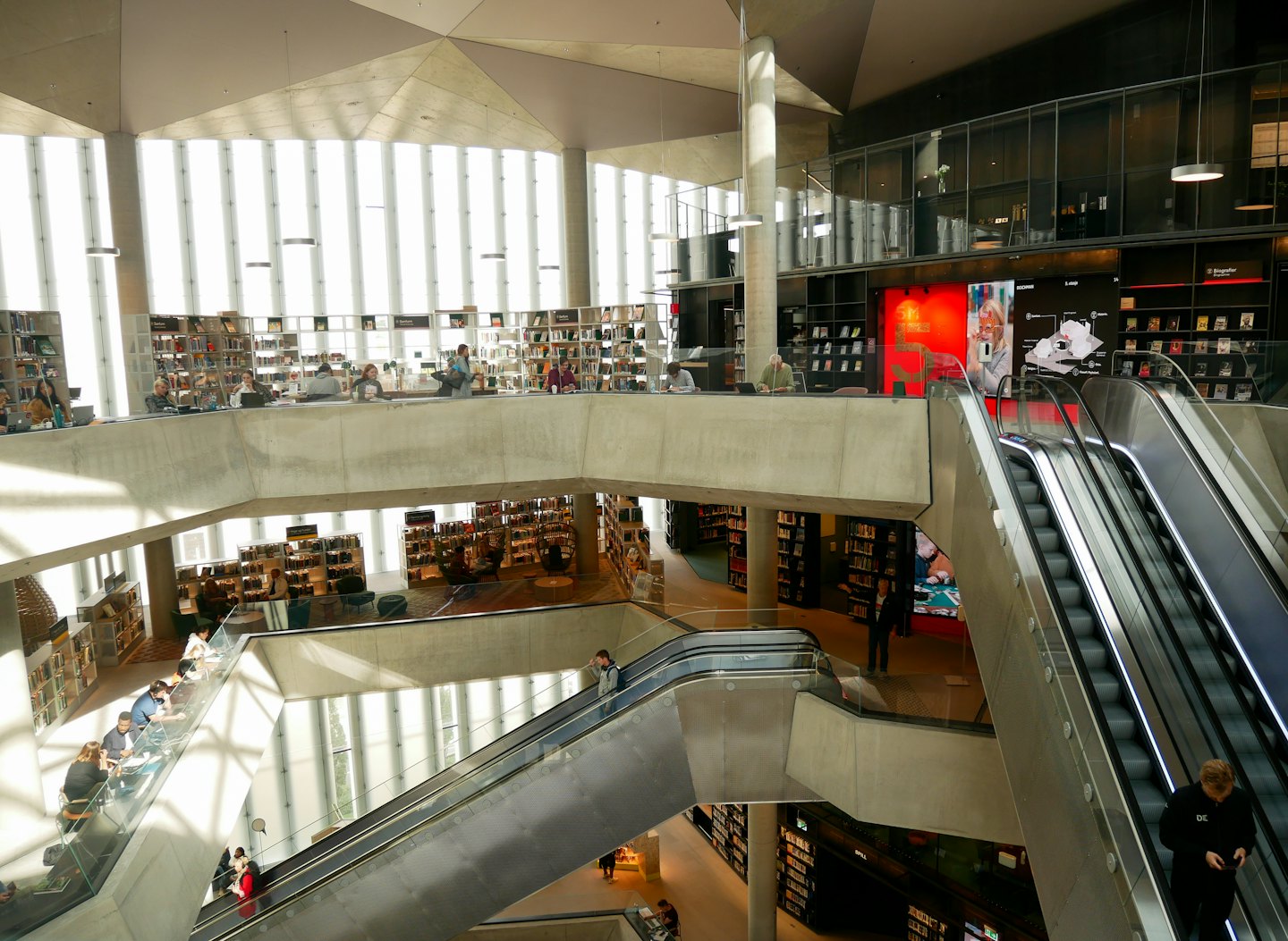 People working and studying in a modern multi-level library.